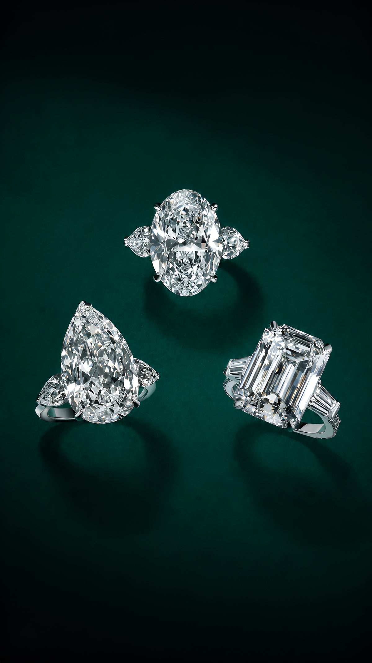 Three diamond engagement rings against a deep green background